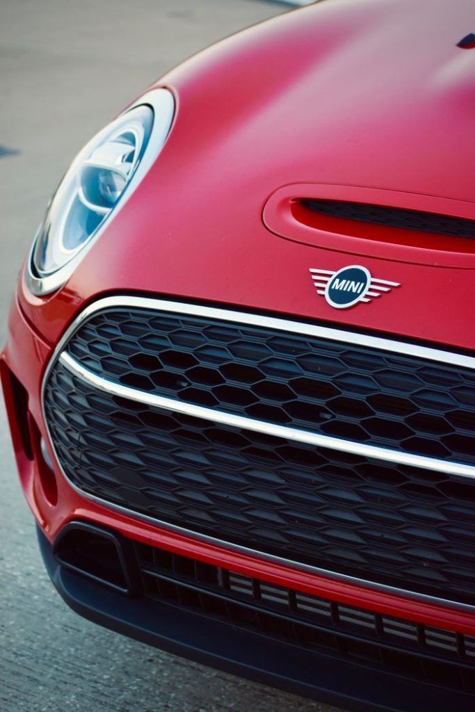 Detailed close-up of a red Mini Cooper showcasing the front grille and headlight.